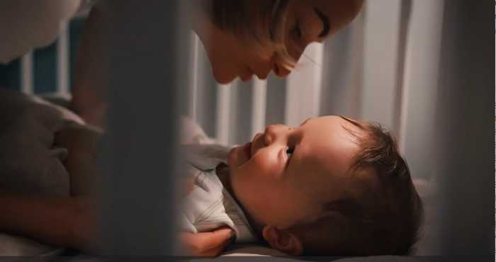 Baby smiling as mother kisses him goodnight