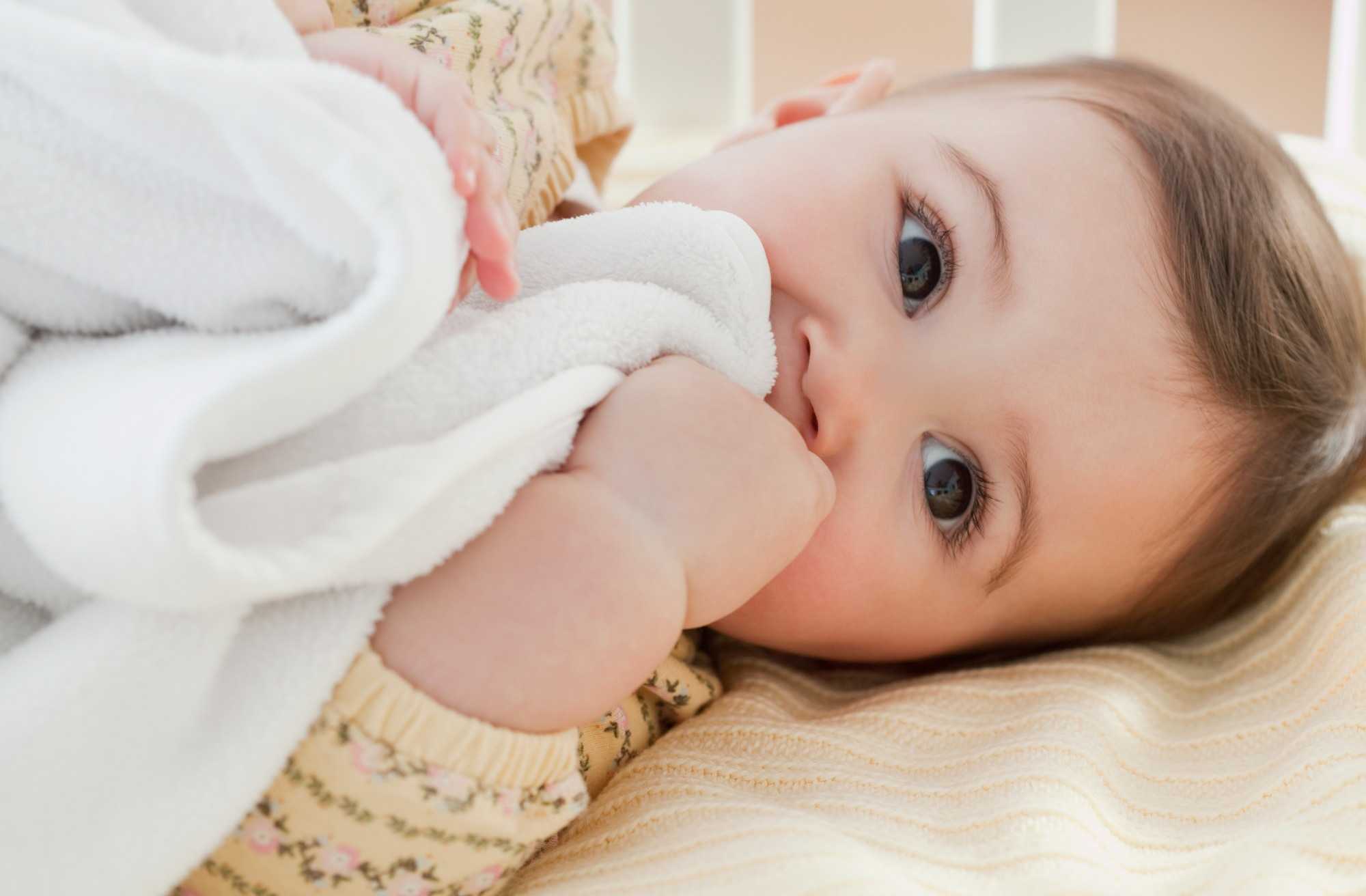 baby lying down holding blanket