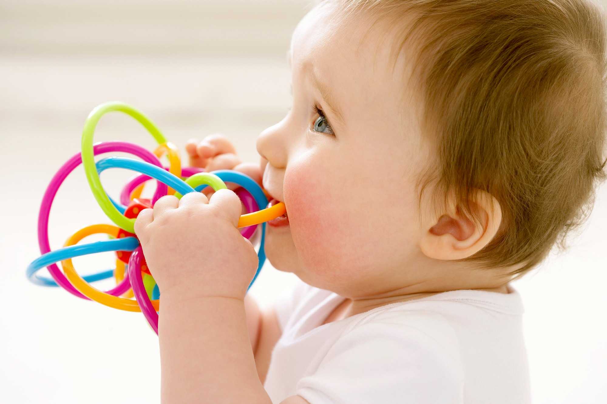 toddler chewing on colourful toy